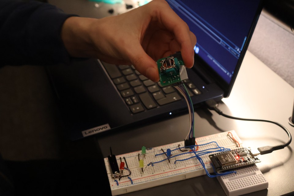 A student connecting a microcontroller beside a laptop and breadboard.