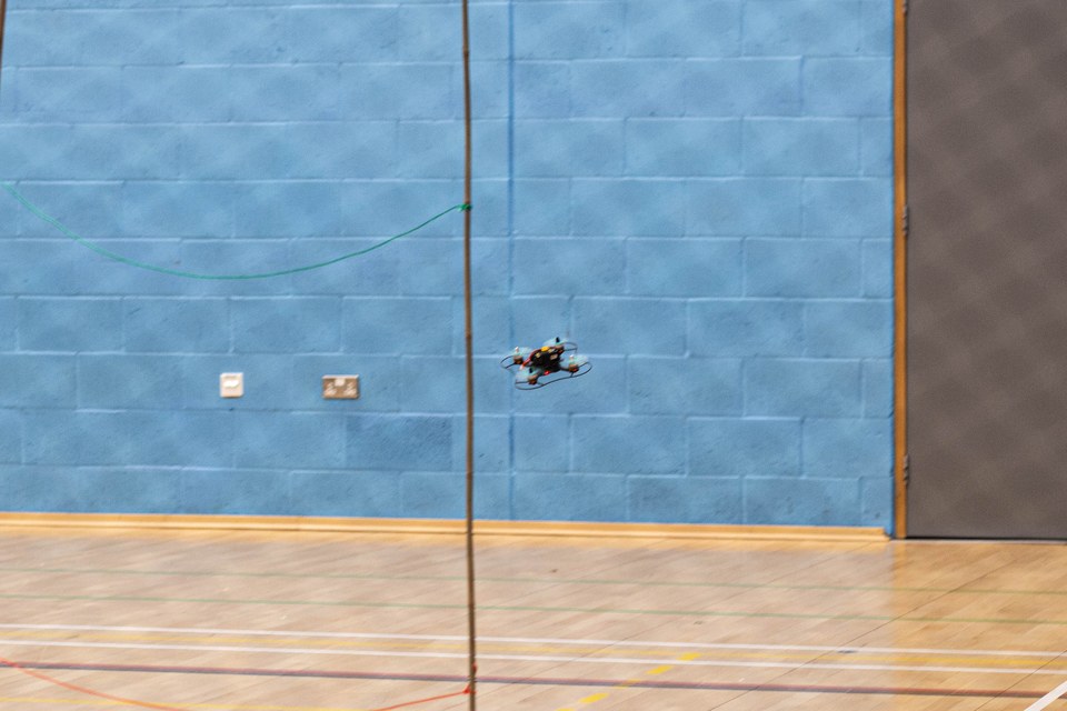 A small quadcopter flying inside a sports hall.