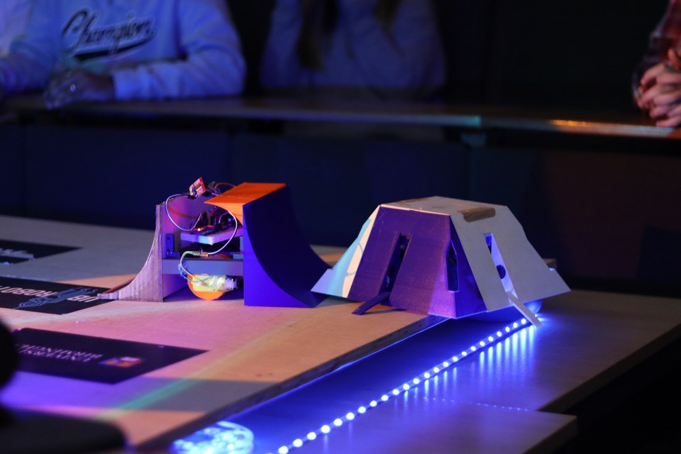 Two student-built Sumobots facing each other under coloured arena lights.