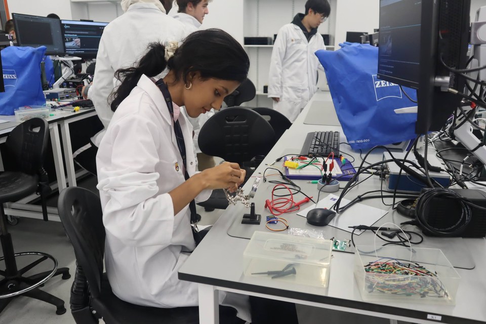 A student assembling a circuit while others work nearby.