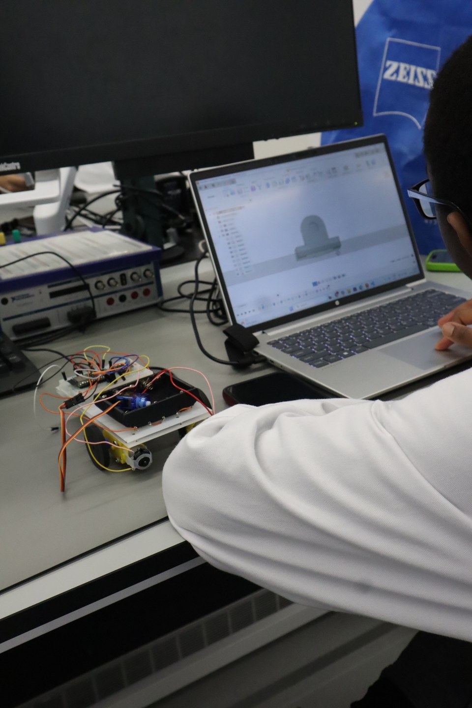 A robot circuit connected beside a laptop and laboratory test equipment.