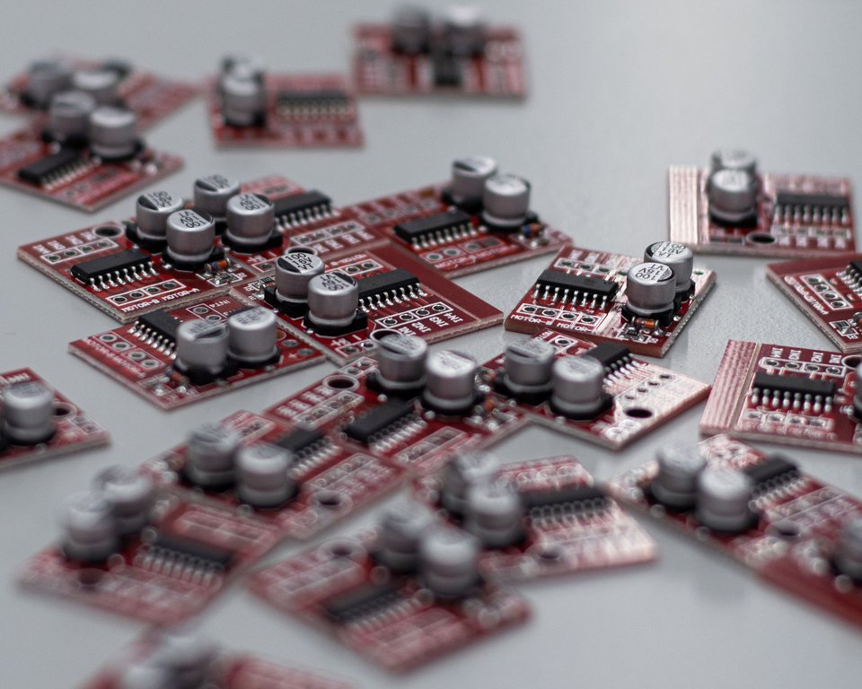 Rows of compact red motor-driver circuit boards arranged on a work surface.