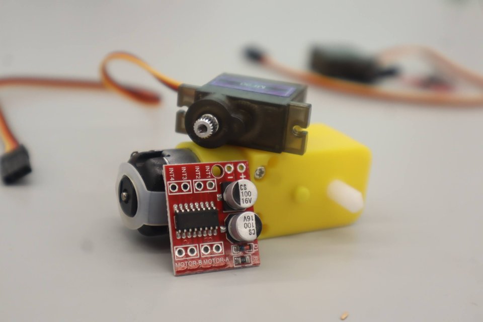 A small motor, servo and red motor-driver board arranged for a workshop.
