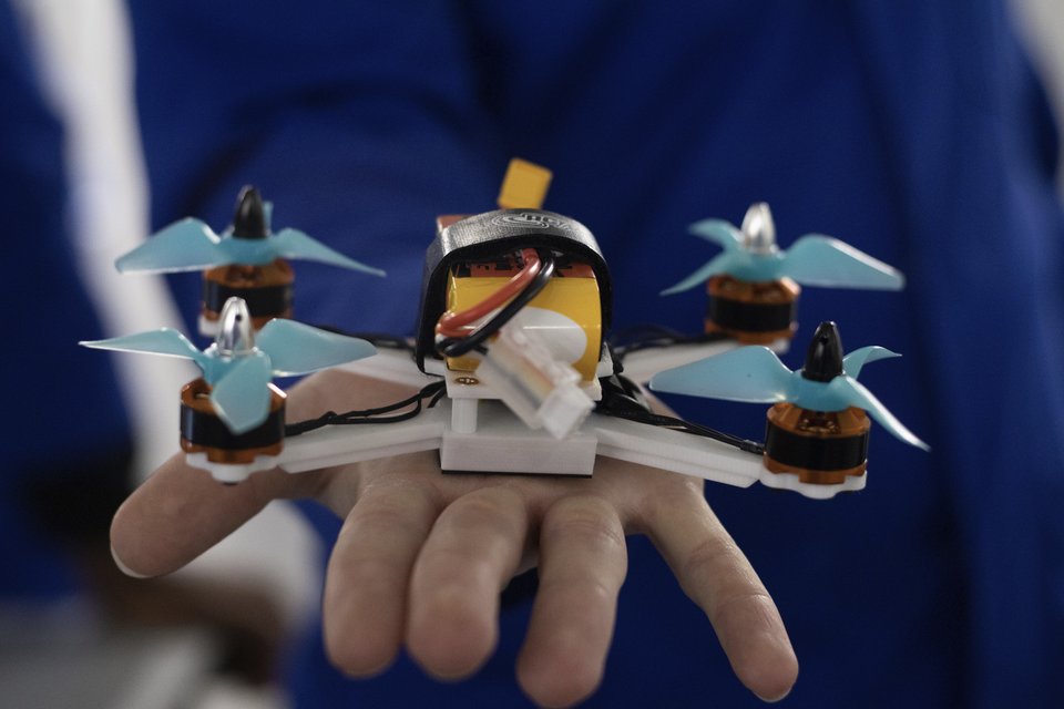 A compact student-built quadcopter resting on a person's hand.