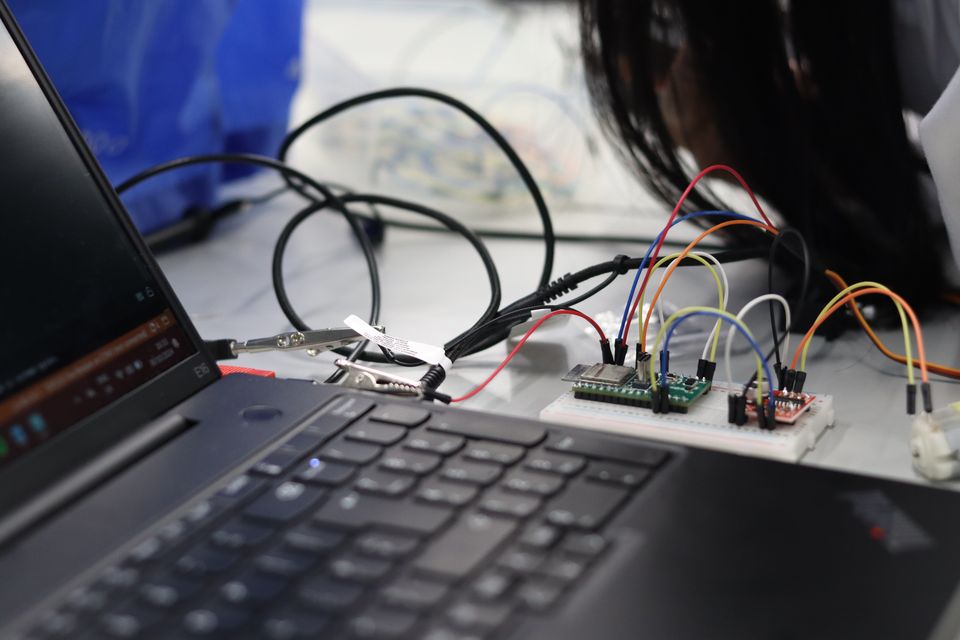 A breadboard circuit connected to a laptop on a workshop bench.