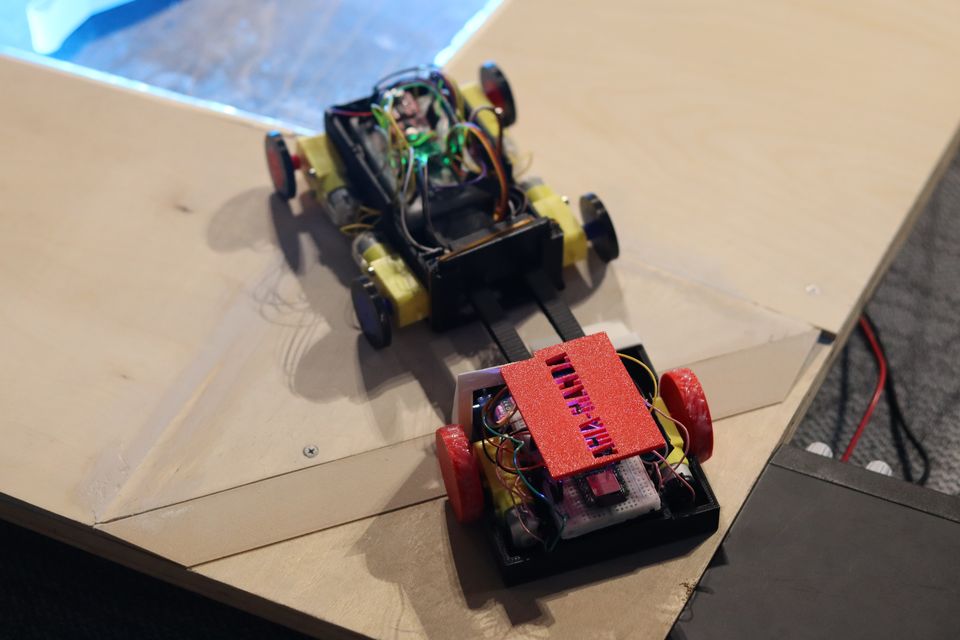 Three compact robots gathered beside a marked competition area.