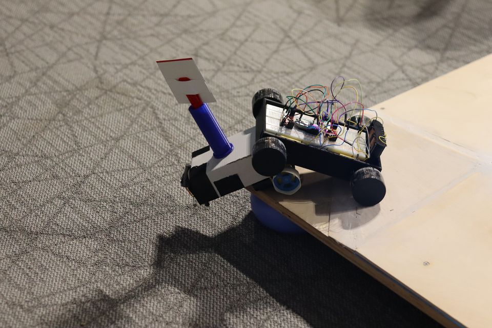 Two student-built robots facing one another on a dark arena surface.