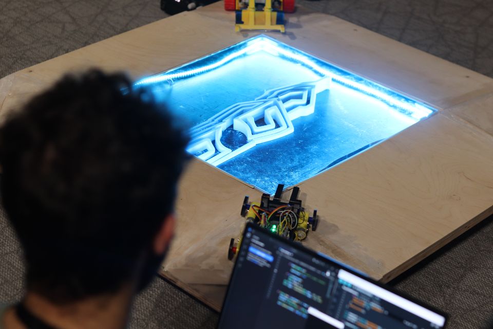 Students and spectators following a robot match beside the arena.