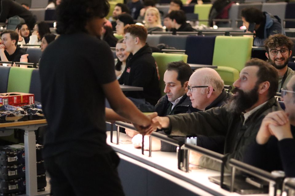 Competitors discussing a match while robots wait on the arena.