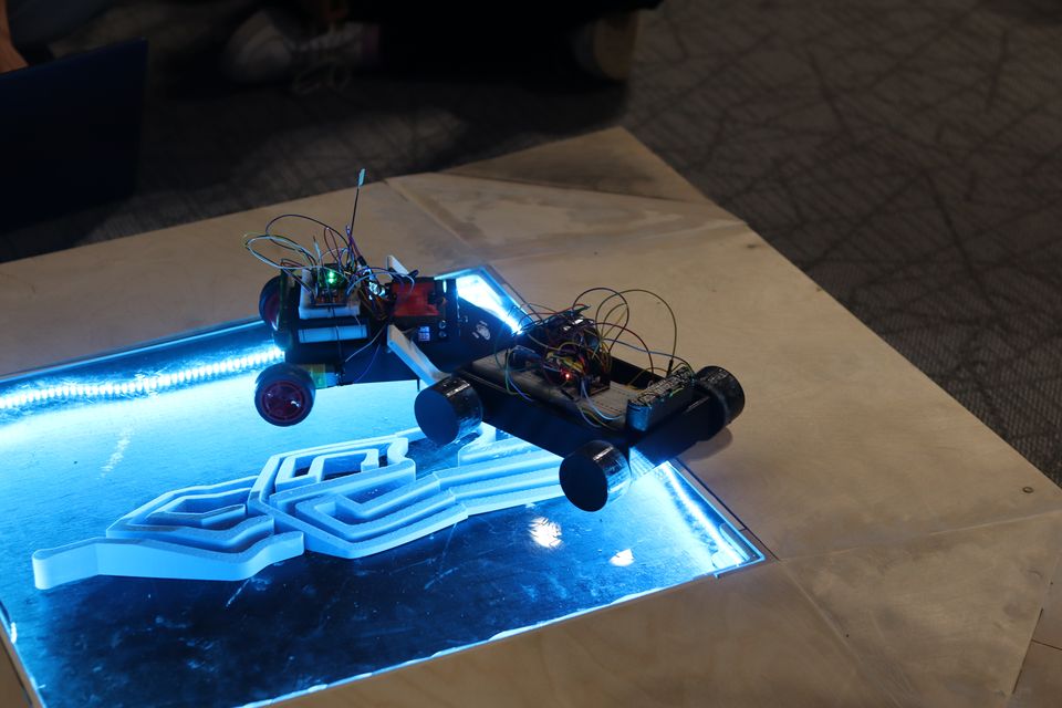 Two robots positioned on a blue illuminated competition surface.