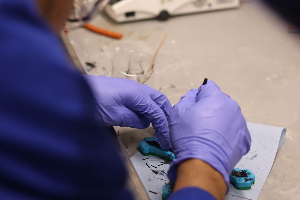 Gloved hands fitting a small component during a practical session.
