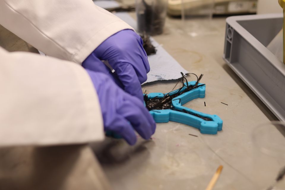 A student in gloves working on a lightweight robot frame.
