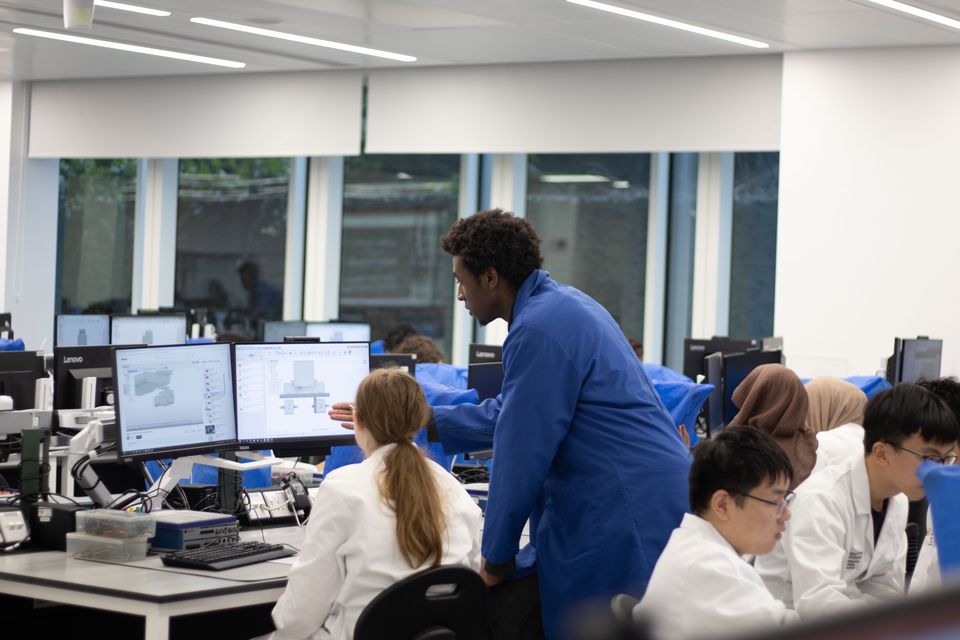 Students collaborating around computers in a practical robotics session.