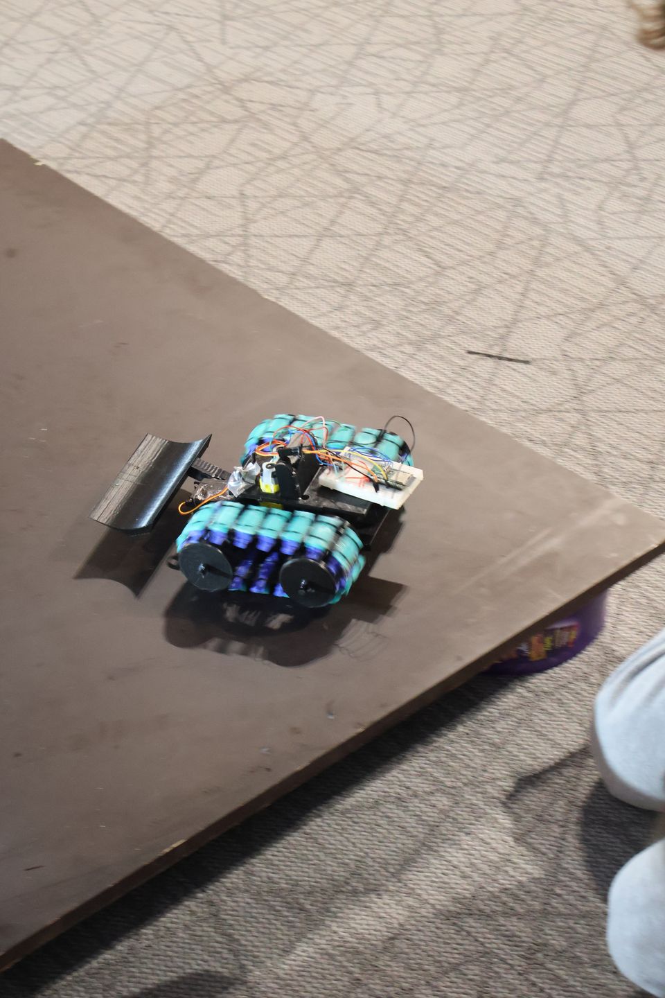 A compact student-built robot standing on the arena surface.