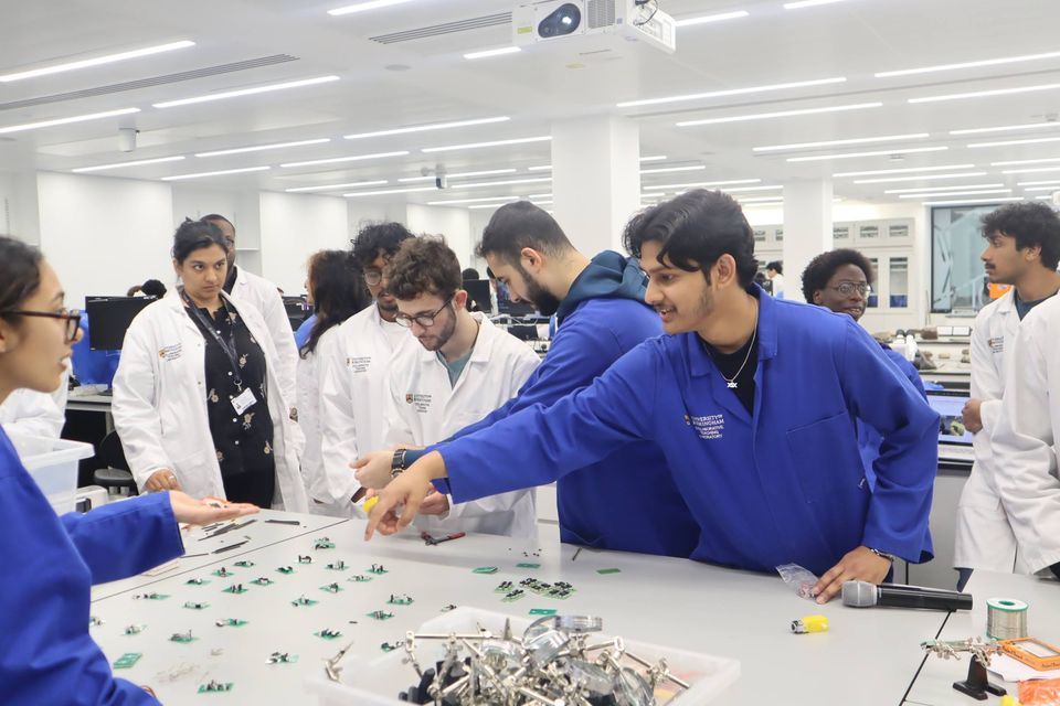Students and society volunteers working together across a robotics laboratory.