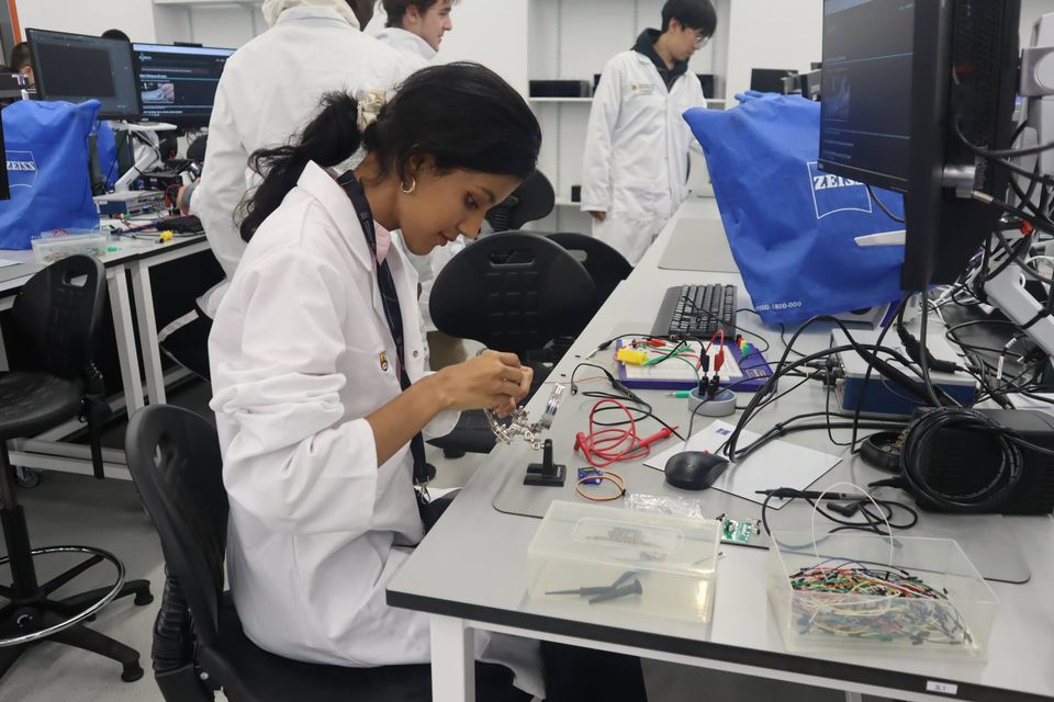 A student assembling a circuit while others work nearby.