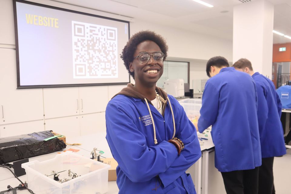 A smiling student in a blue laboratory coat during a workshop.