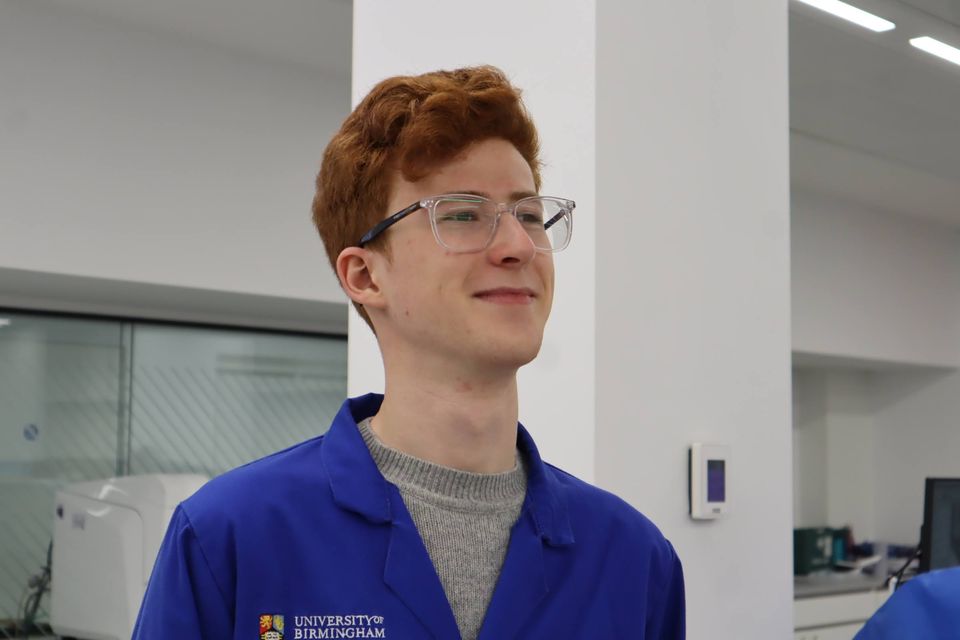 A student in a blue laboratory coat smiling during the workshop.