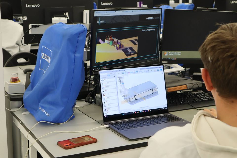 A laptop displaying a CAD model beside workshop equipment.