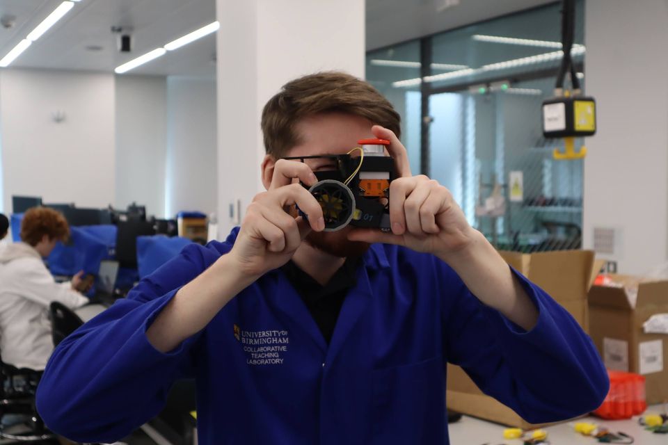 A student taking a photograph during a practical robotics session.