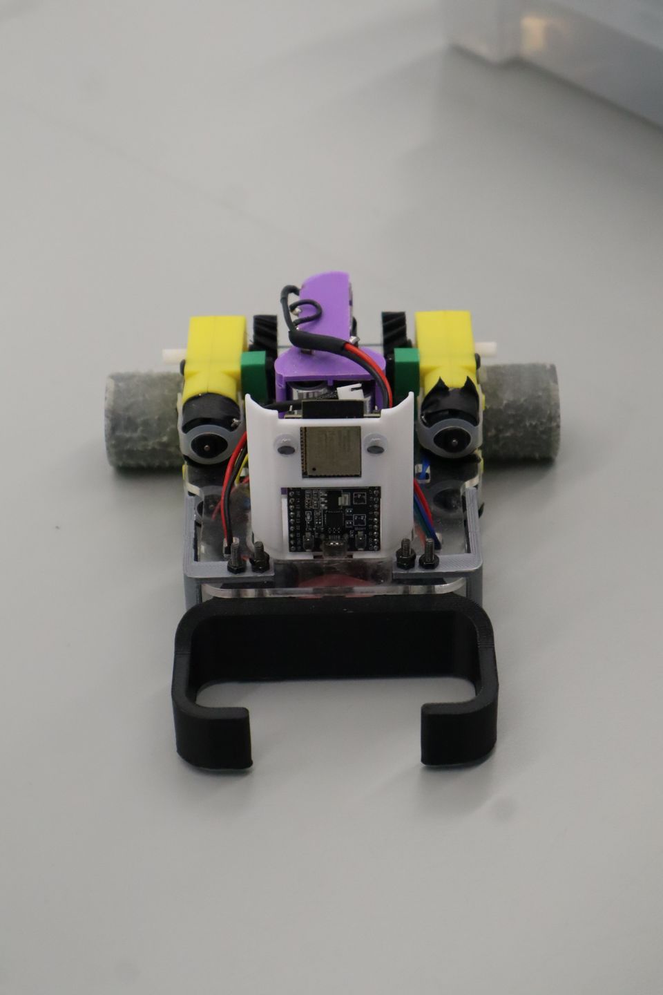 Top-down view of a small wheeled robot with exposed electronics.
