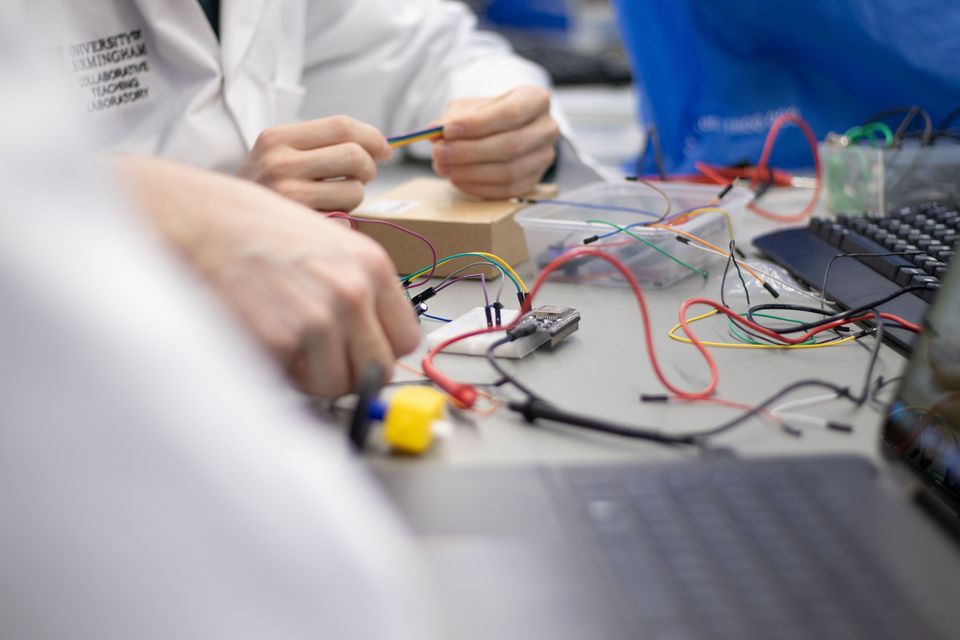 Hands connecting wires to a breadboard circuit during a workshop.