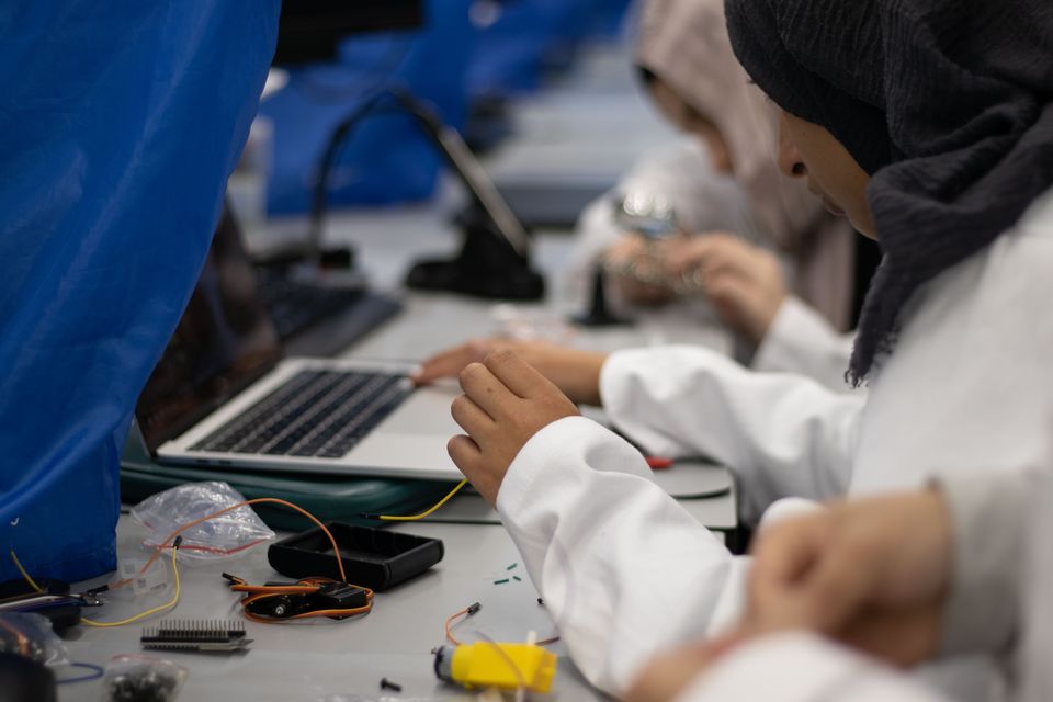 Students working with tools and electronics across a shared bench.