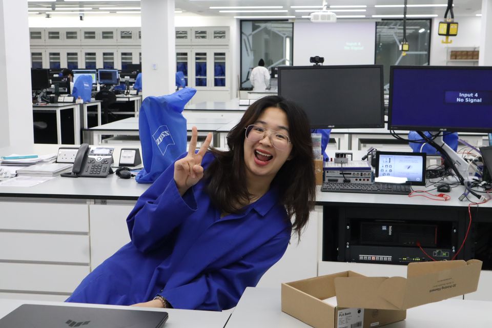 A smiling student leaning beside equipment in the robotics laboratory.