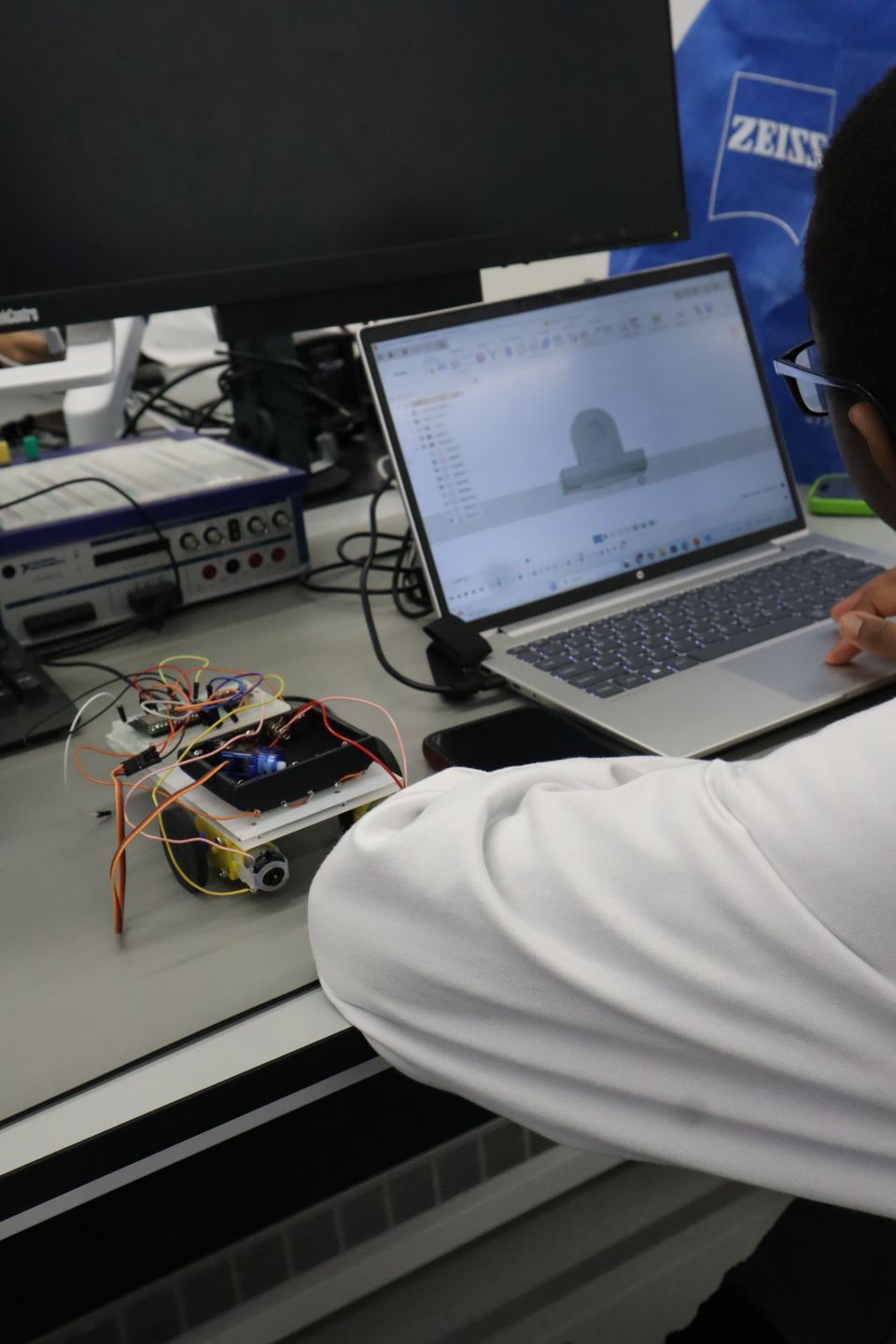 A robot circuit connected beside a laptop and laboratory test equipment.
