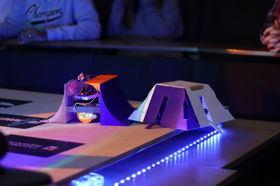Two student-built Sumobots facing each other under coloured arena lights.